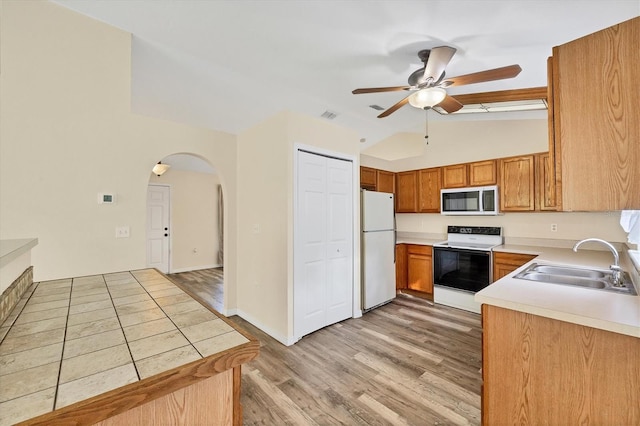 3768 Billingham Ln, North Port, FL 34288 - kitchen featuring vaulted ceiling, white appliances, ceiling fan, light wood-style flooring, and arched walkways