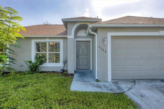 3768 Billingham Ln, North Port, FL 34288 - doorway to property featuring stucco siding, a garage, a shingled roof, and a lawn