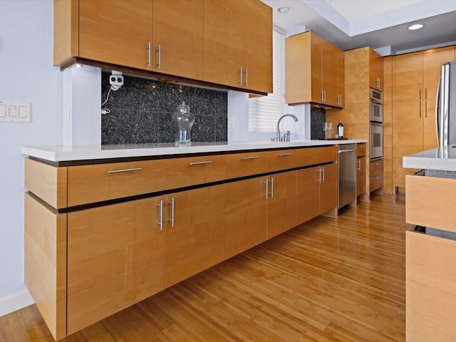 8041 Bay Pointe Dr, Englewood, FL 34224 - kitchen featuring appliances with stainless steel finishes, light wood-style floors, tasteful backsplash, light countertops, and recessed lighting