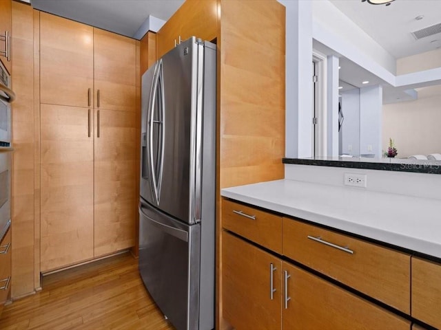 8041 Bay Pointe Dr, Englewood, FL 34224 - kitchen featuring stainless steel fridge with ice dispenser, light wood finished floors, brown cabinets, and light countertops