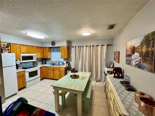 26591 Fairway Dr Unit A & B, Punta Gorda, FL 33982 - kitchen featuring white appliances, light countertops, brown cabinets, light tile patterned flooring, and a textured ceiling