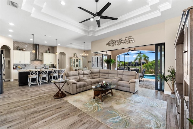 15044 San Domingo Blvd, Port Charlotte, FL 33981 - living room featuring arched walkways, a raised ceiling, ceiling fan, crown molding, and light wood-style floors