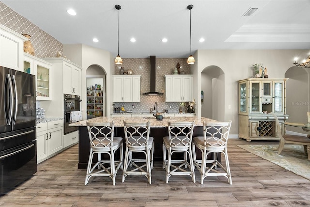 15044 San Domingo Blvd, Port Charlotte, FL 33981 - kitchen with freestanding refrigerator, wall chimney exhaust hood, arched walkways, a kitchen island with sink, and a breakfast bar area