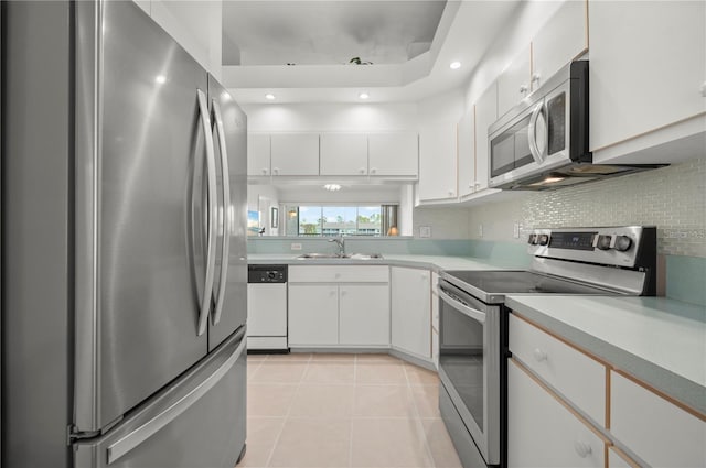 11644 SW Egret Cir Unit 905, Lake Suzy, FL 34269 - kitchen with stainless steel appliances, light countertops, light tile patterned flooring, white cabinetry, and backsplash
