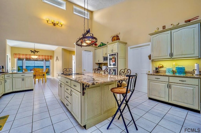 kitchen featuring pendant lighting, light tile patterned floors, light stone counters, and a high ceiling