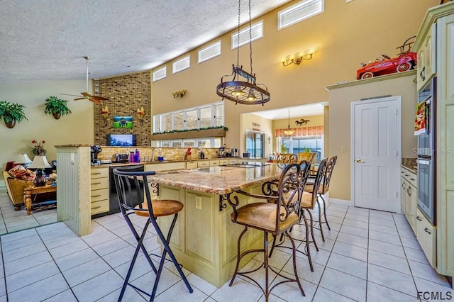 kitchen featuring light tile patterned flooring, a kitchen breakfast bar, kitchen peninsula, pendant lighting, and black appliances