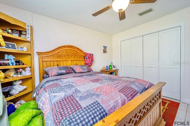 tiled bedroom featuring ceiling fan and a closet