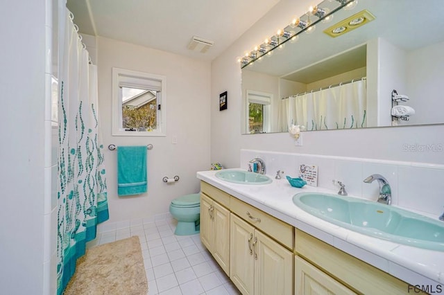 bathroom with vanity, plenty of natural light, tile patterned floors, and toilet