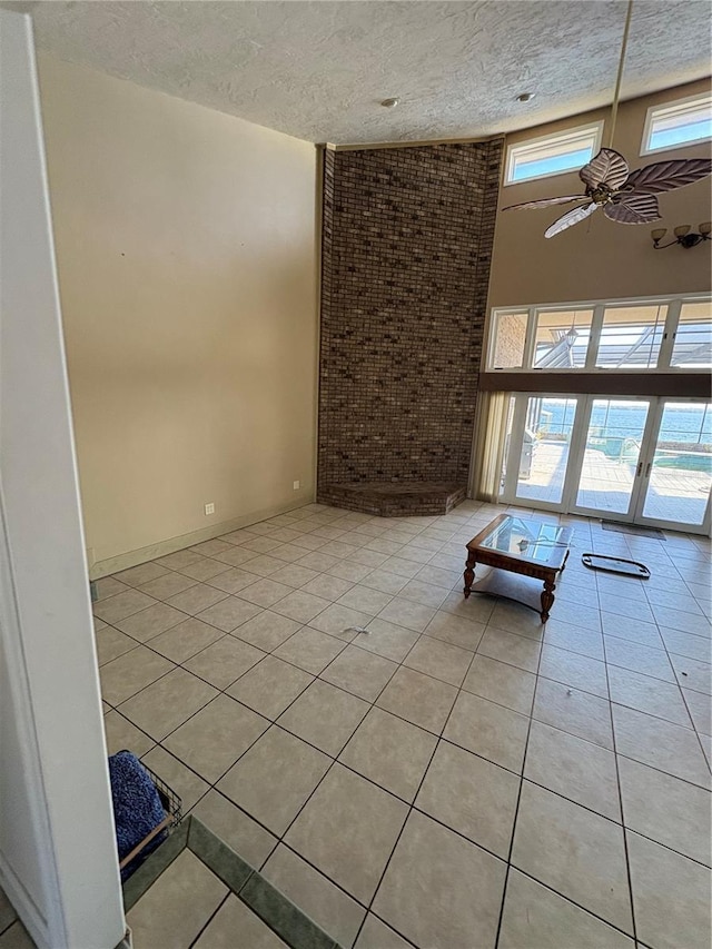 spare room with ceiling fan, brick wall, light tile patterned floors, and a textured ceiling