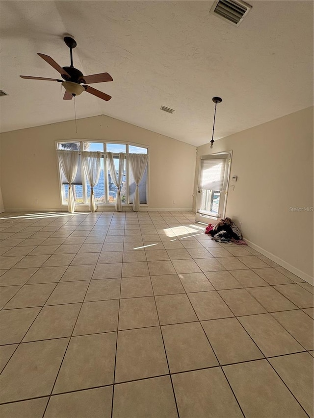 empty room featuring light tile patterned flooring, ceiling fan, lofted ceiling, and a wealth of natural light