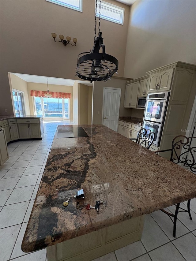 kitchen with light tile patterned floors, a towering ceiling, and plenty of natural light