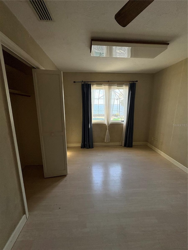 unfurnished bedroom featuring light hardwood / wood-style floors, a closet, and ceiling fan