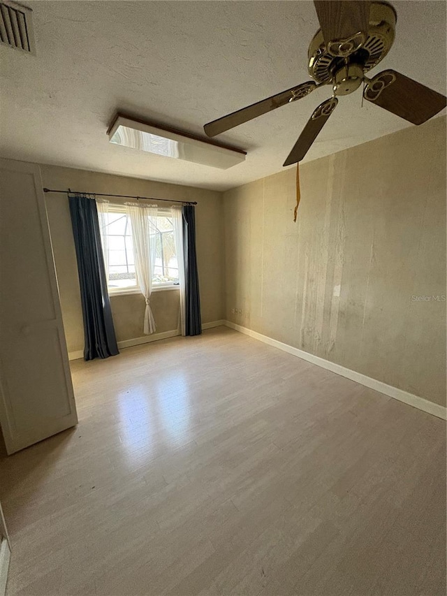 unfurnished room with ceiling fan, light hardwood / wood-style floors, and a textured ceiling