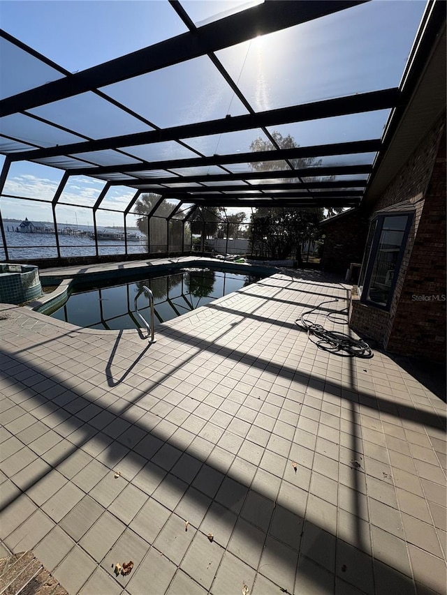 view of swimming pool featuring a hot tub, a patio, a water view, and glass enclosure