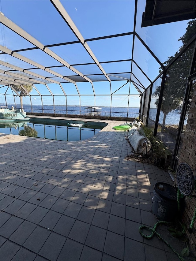 view of pool with a patio, a water view, and glass enclosure