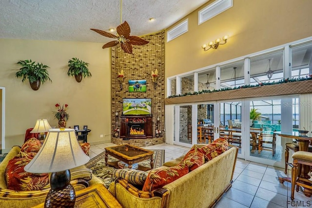 living room featuring light tile patterned flooring, high vaulted ceiling, a fireplace, ceiling fan, and a textured ceiling