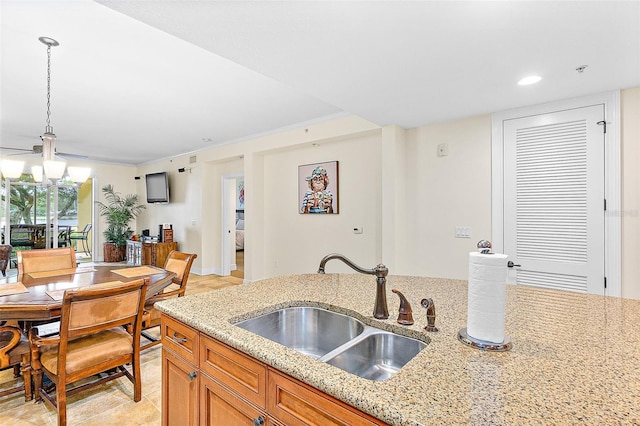 kitchen with light stone counters, sink, hanging light fixtures, and a notable chandelier