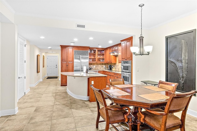 kitchen featuring tasteful backsplash, sink, hanging light fixtures, a kitchen island with sink, and stainless steel appliances