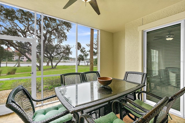 sunroom / solarium featuring ceiling fan and a water view