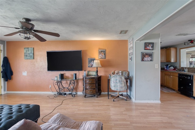 living room with a textured ceiling, ceiling fan, sink, and light hardwood / wood-style flooring