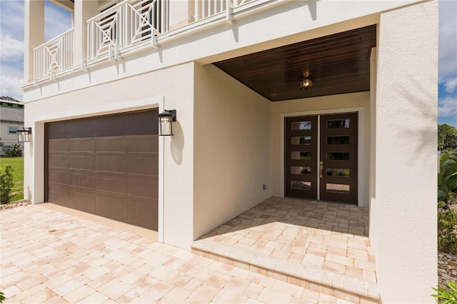 property entrance featuring a garage, a balcony, and stucco siding