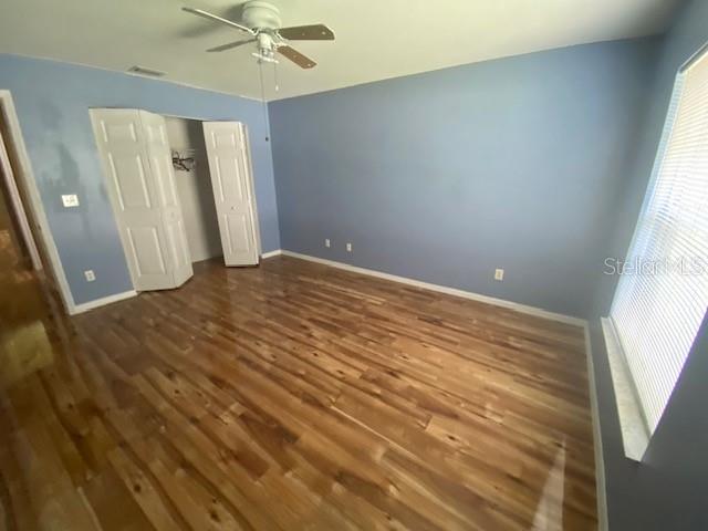 unfurnished bedroom with ceiling fan and dark wood-type flooring