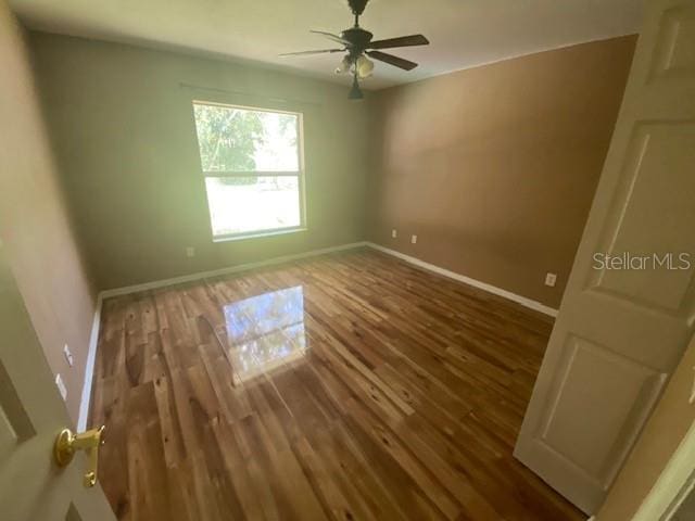 empty room with dark hardwood / wood-style flooring and ceiling fan