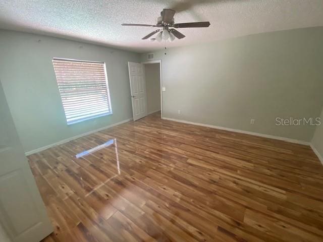 empty room with a textured ceiling, ceiling fan, and hardwood / wood-style flooring