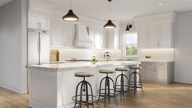 kitchen with premium range hood, a kitchen island, decorative light fixtures, and a breakfast bar