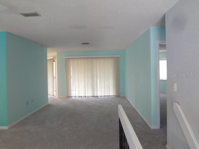 carpeted empty room with a textured ceiling