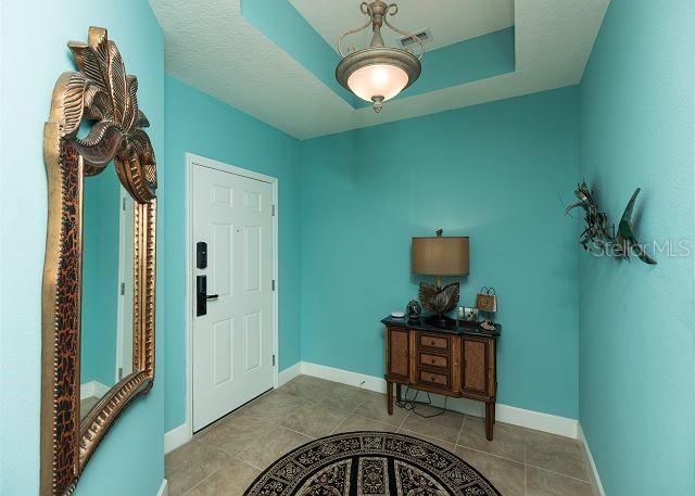 foyer with light tile floors and a tray ceiling