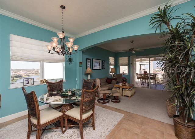 dining space with light tile floors, ceiling fan with notable chandelier, a healthy amount of sunlight, and ornamental molding