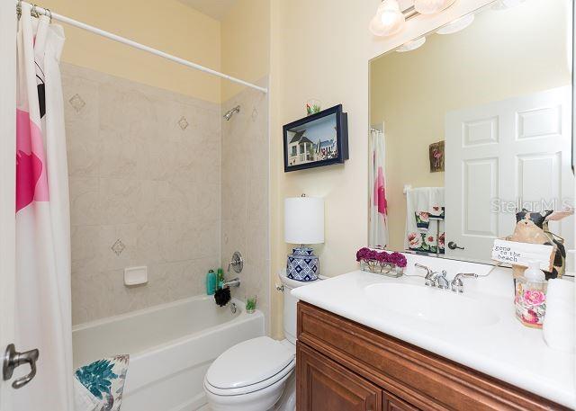 full bathroom featuring shower / bath combination with curtain, toilet, and vanity