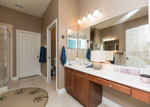 bathroom featuring walk in shower, tile flooring, dual sinks, and vanity with extensive cabinet space