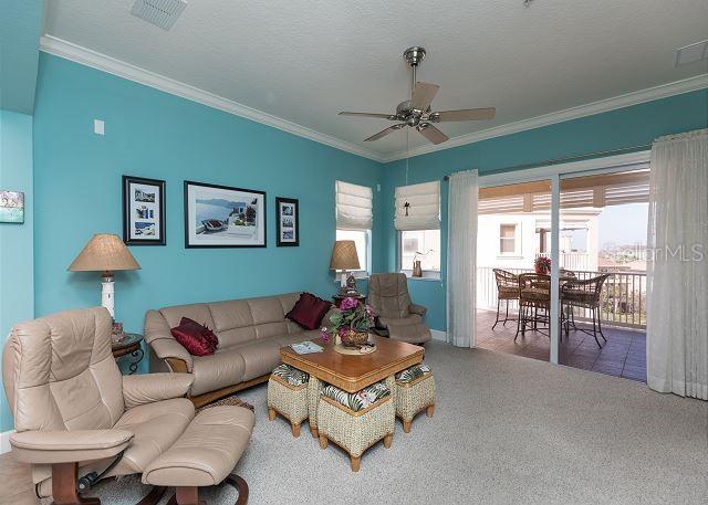 living room with carpet floors, ceiling fan, a textured ceiling, and crown molding