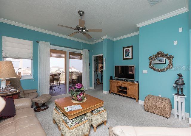 living room with light carpet, ornamental molding, a textured ceiling, and ceiling fan