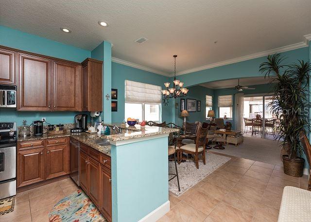 kitchen featuring light tile flooring, decorative light fixtures, ceiling fan with notable chandelier, and appliances with stainless steel finishes