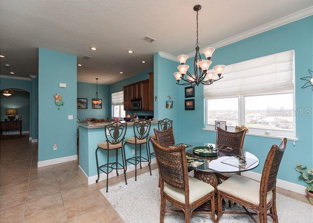 tiled dining area featuring a chandelier, a textured ceiling, and crown molding