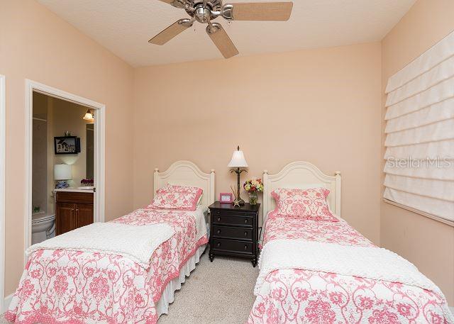 carpeted bedroom featuring ensuite bathroom and ceiling fan