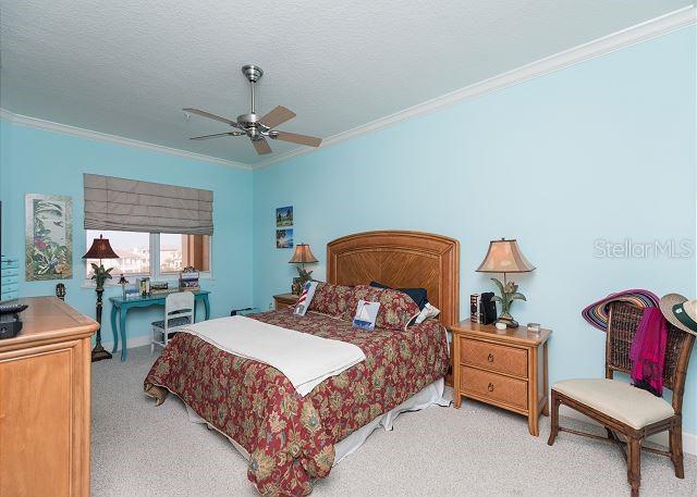 bedroom featuring crown molding, a textured ceiling, light colored carpet, and ceiling fan