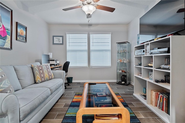 living room with ceiling fan and a textured ceiling