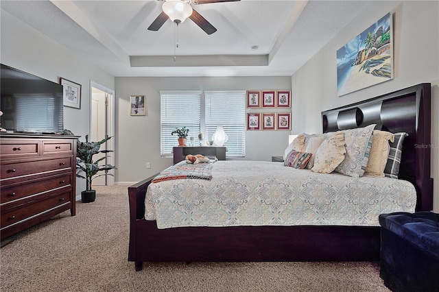 bedroom with carpet flooring, a raised ceiling, and ceiling fan