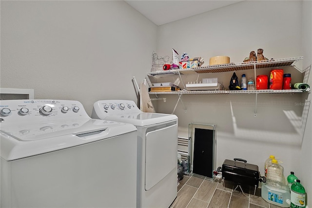 laundry room with washing machine and clothes dryer and hardwood / wood-style floors