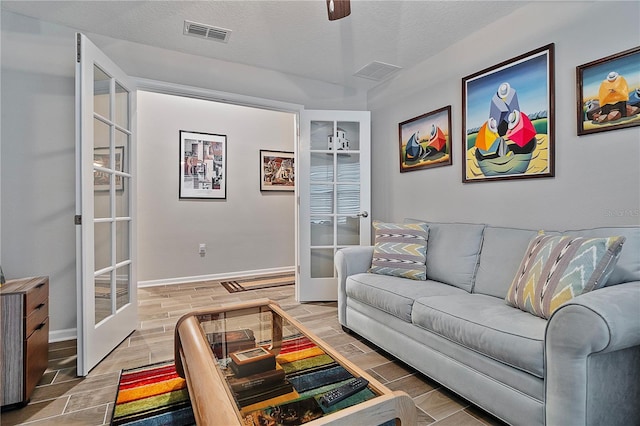 living room featuring french doors, a textured ceiling, ceiling fan, and wood-type flooring