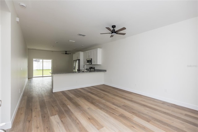 unfurnished living room with light wood-type flooring, sink, and ceiling fan