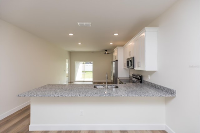 kitchen with white cabinetry, appliances with stainless steel finishes, light wood-type flooring, sink, and kitchen peninsula