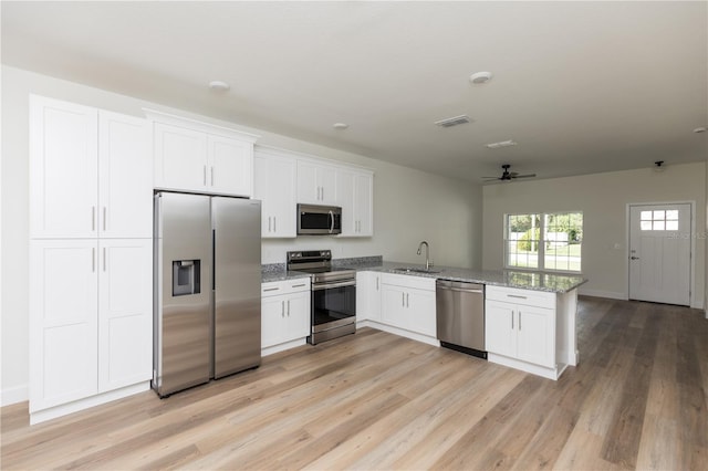 kitchen featuring stainless steel appliances, light hardwood / wood-style floors, white cabinets, kitchen peninsula, and sink