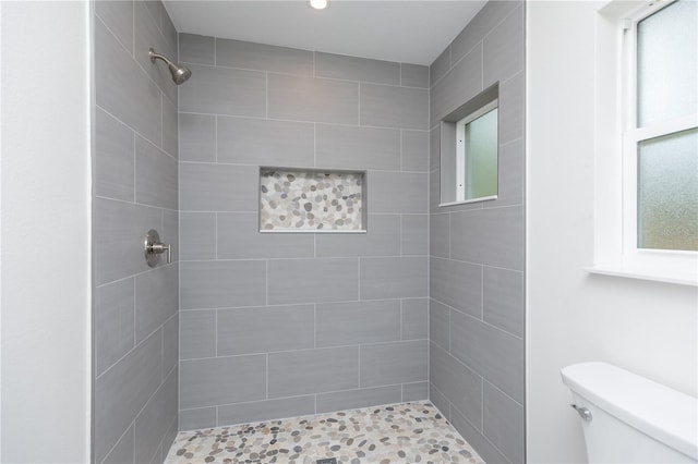 bathroom with toilet and a tile shower