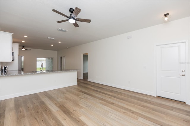 unfurnished living room featuring ceiling fan, sink, and light wood-type flooring