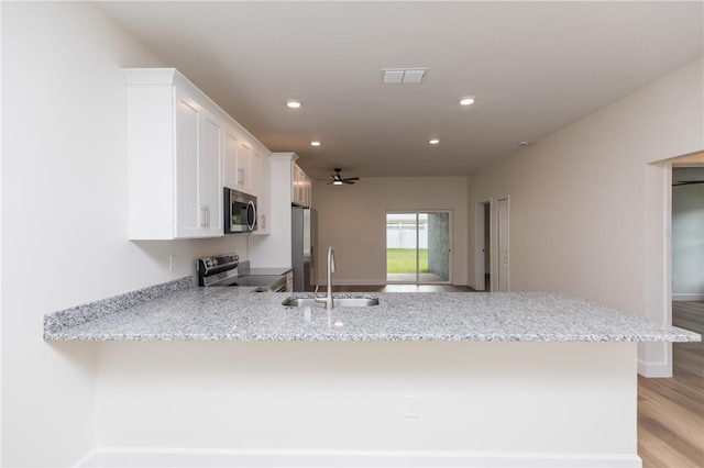 kitchen featuring stainless steel appliances, sink, kitchen peninsula, light hardwood / wood-style flooring, and white cabinets